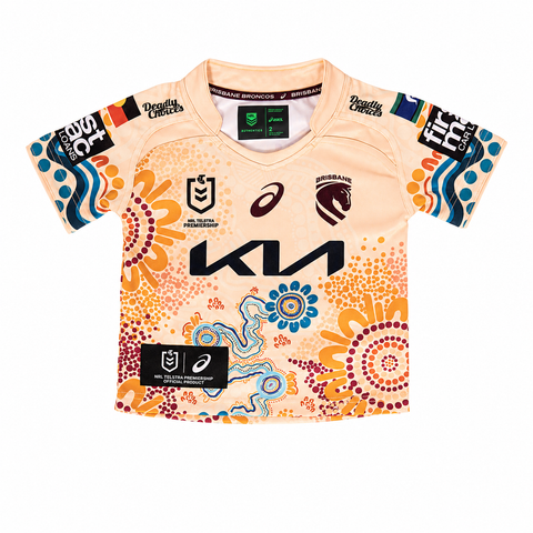 A youth Australia rugby jersey in a light peach color with a vibrant Aboriginal-inspired dot art pattern in orange, yellow, blue, and red. It features the Kia logo on the front, the Brisbane Broncos team crest, and sponsor logos including Asics, Destiny Centers, and MTN.