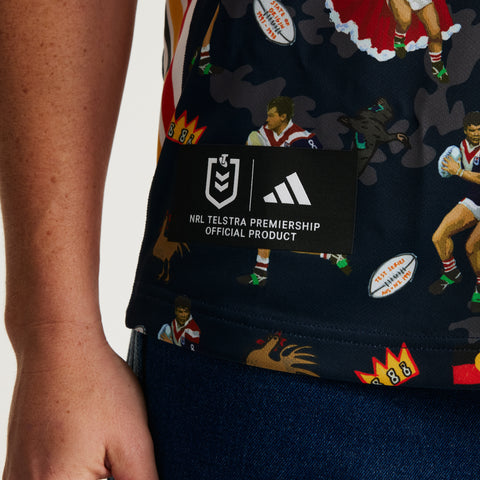Close-up of a person wearing a navy blue Adidas NRL Telstra Premiership jersey with a multicolor rugby player and ball print, featuring a black official product label on the chest.